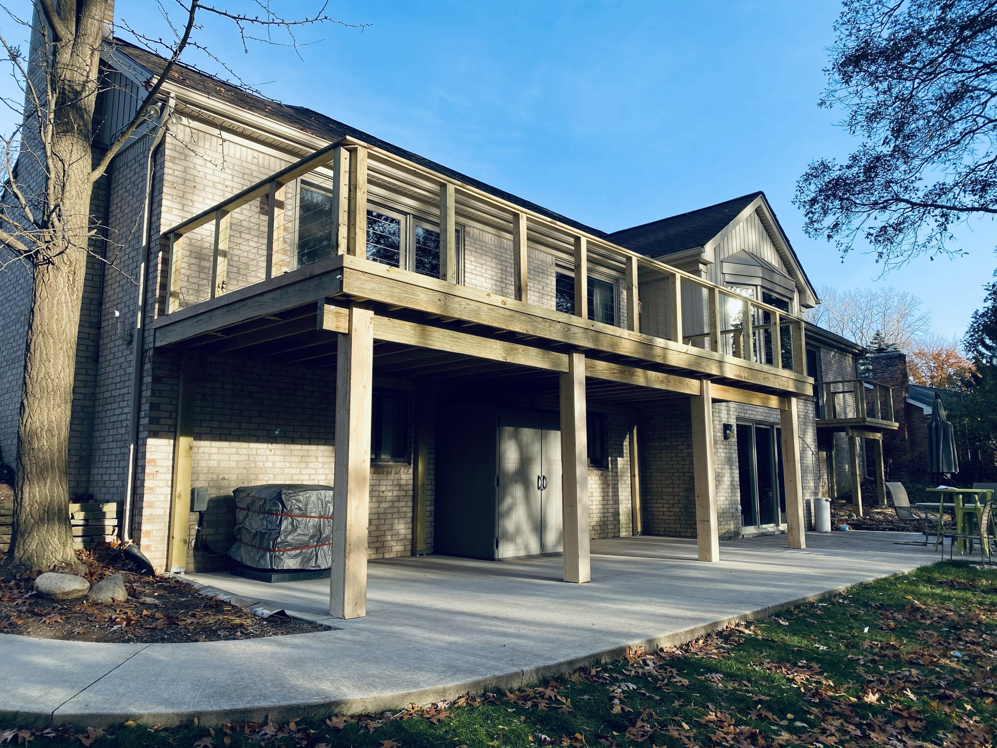 Elevated multi-tier deck system with upper screened porch enclosure and open lower deck level, pressure-treated wood framing attached to a two-story brick colonial home: built by JD Contracting LLC