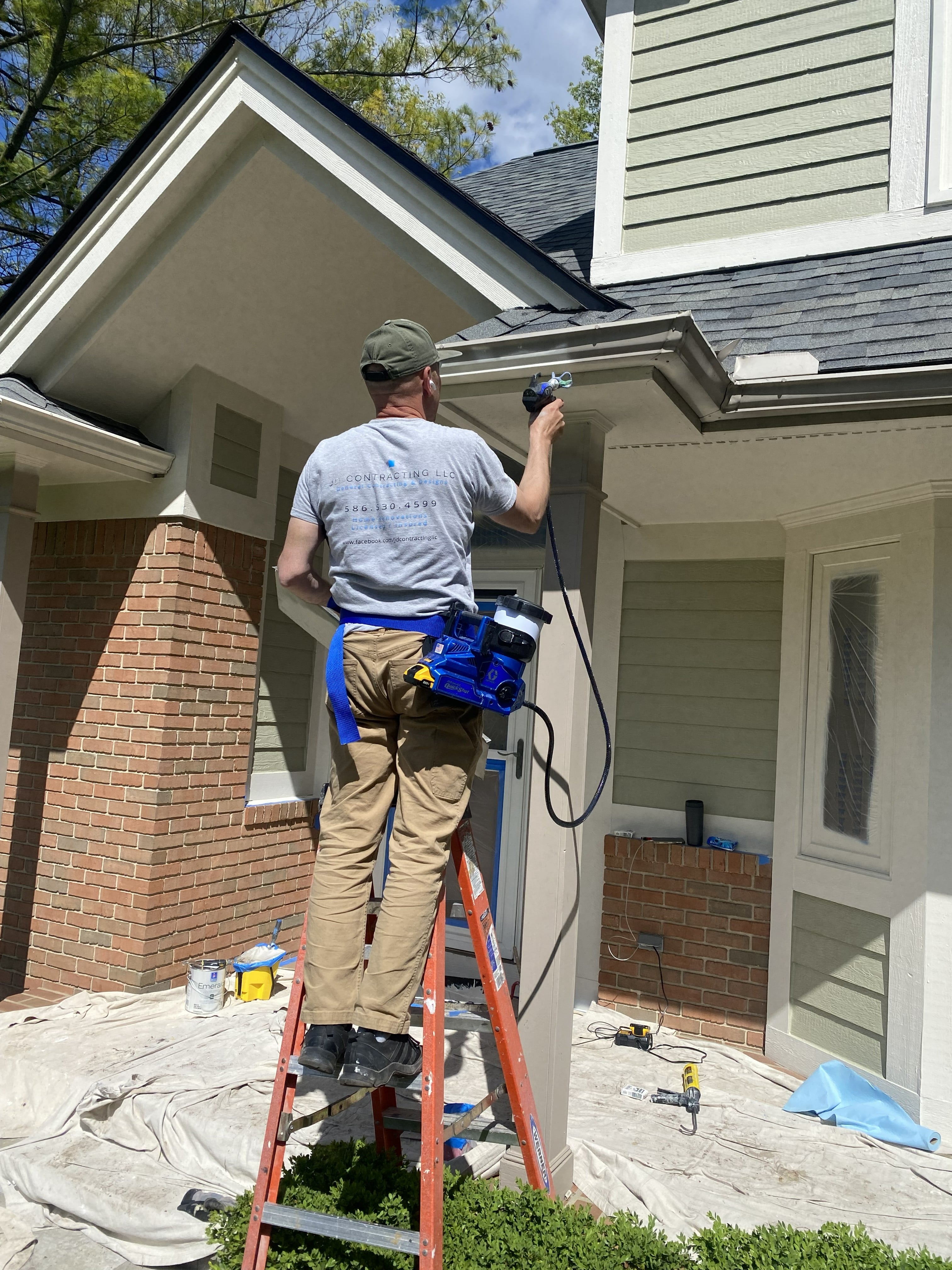 Freshly painted two-story home exterior with white lap siding, upper-level deck, and updated trim: exterior painting by JD Contracting LLC