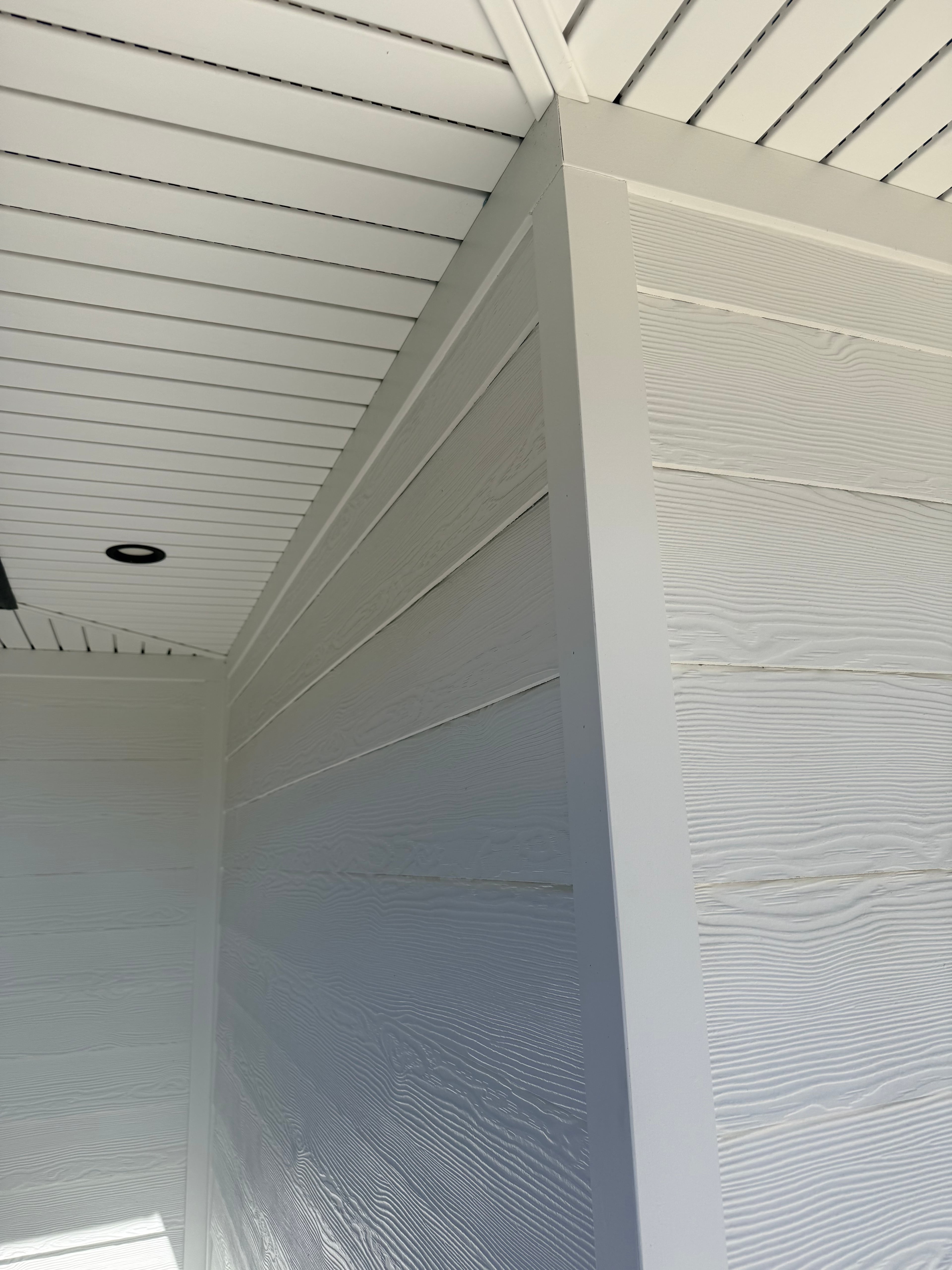 Close-up corner detail of white fiber cement board-and-batten siding installation with clean trim and fascia work: installed by JD Contracting LLC